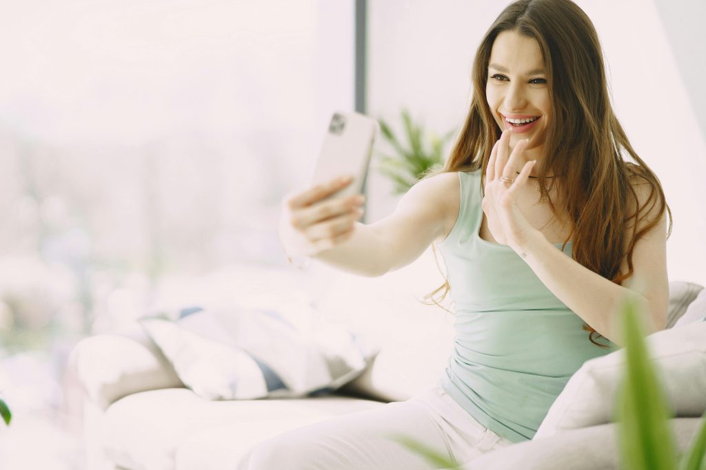 Cheerful young woman using smartphone during video call